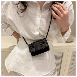 Detail view of a black mini crossbody bag with leather texture and retro buckle straps