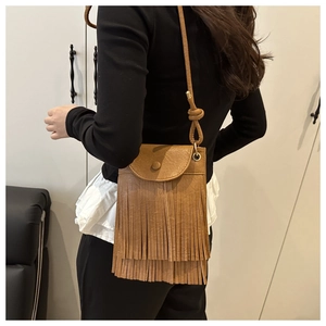 Detail of brown faux leather crossbody bag with double-layered long fringe and flap closure