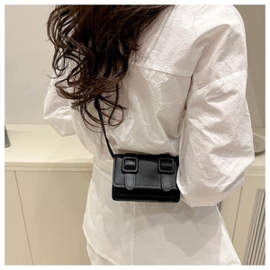 Close-up of a mini black leather crossbody bag with dual matte resin buckles