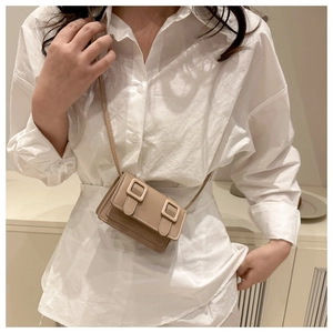 Detail of mini beige crossbody bag showing high-quality faux leather and square buckles