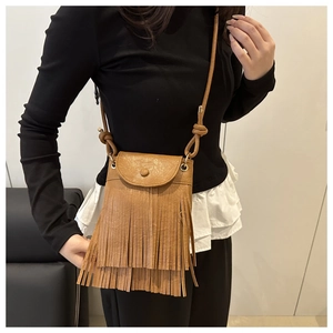Detail of a brown leather crossbody bag featuring double-layered tassels and a magnetic flap