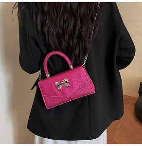 Détail d'un sac fuchsia pailleté avec nœud papillon argenté et bandoulière chaîne