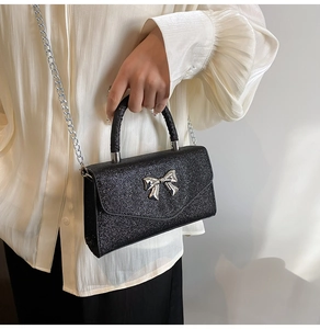 Détail du sac noir pailleté avec nœud argenté et bandoulière en chaîne métallique