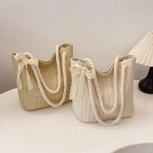 Straw woven tote bag with rope handles and lace bow detail for a bohemian summer look