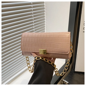 Detailopname van roze baguette tas met krokodillenprint en gouden metalen ketting