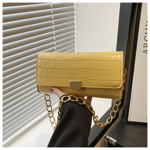 Detail van gele baguette tas met krokodillenpatroon gouden ketting en metalen sluiting