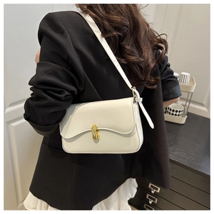 Detail of cream leather shoulder bag with gold oval twist lock worn by a model in a suit