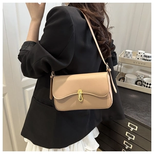 Chic beige baguette bag with gold metal buckle worn by a woman in professional attire