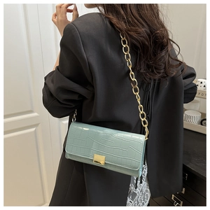 Detail of mint blue crocodile pattern baguette bag with golden chain and square buckle