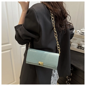 Detail of mint green crocodile embossed small square bag with gold chain strap