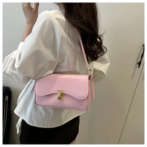 Detail of pink matte leather shoulder bag with gold metal lock on a model outfit