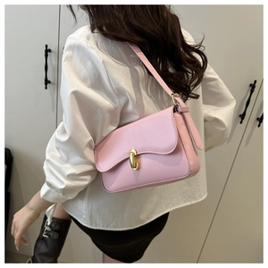 Pink minimalist shoulder bag with gold clasp shown on a white shirt model