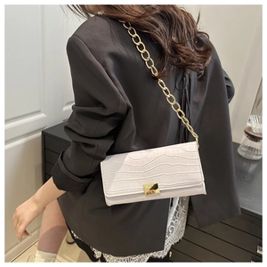Detail of white crocodile embossed texture on flap bag with gold chain strap