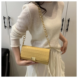 Pale yellow crocodile pattern shoulder bag with gold chain strap on a white knit outfit