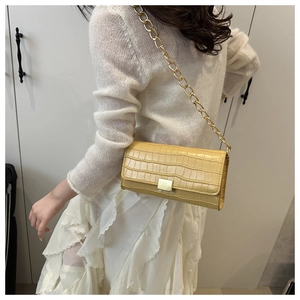 Gros plan du sac bandoulière jaune texture crocodile avec chaîne dorée et fermoir métal