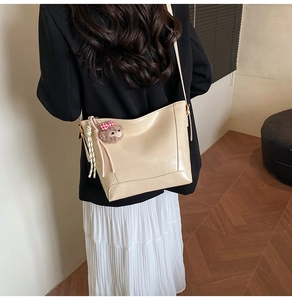 Detail of cream beige tote bag with cute brown plush lamb pendant on a black suit model
