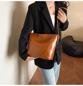Brown oil wax leather bucket bag worn by model with casual suit for daily commuting