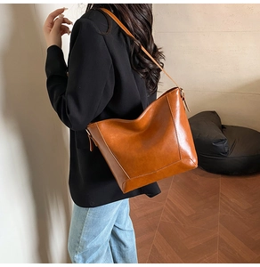 Brown vintage oil wax leather tote bag shown on a model's shoulder in indoor light