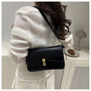 Detail of minimalist black leather shoulder bag with elegant oval gold metal buckle clasp