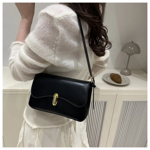 Detail of a black leather shoulder bag with wave-edge flap and golden metal buckle
