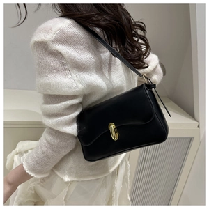 Detail of minimalist black leather underarm bag with a golden metal buckle on a model