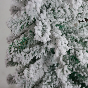 Close-up of artificial flocked Christmas tree needles with realistic white snow texture