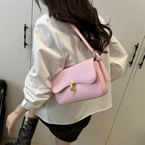 Pink leather underarm bag with gold U-shaped clasp shown on model for daily style