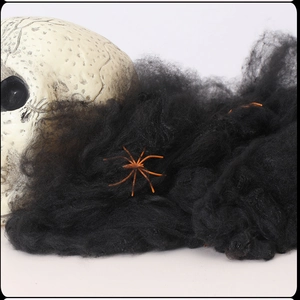 Close-up of black stretchable spider web with orange spiders on a skull prop