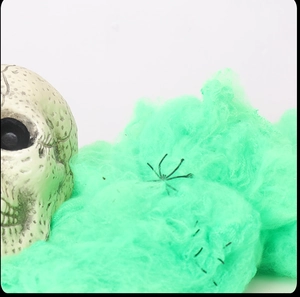 Macro detail of neon green Halloween cobwebs with small black spiders and a skull prop