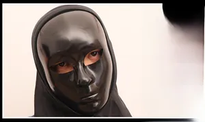 Detail of a glossy black full face mask with 3D contours and an integrated black fabric hood