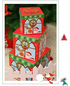 Three-piece stackable red and green Christmas gift box set on a white faux fur rug
