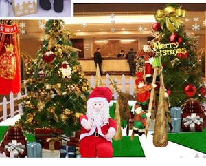 Detail of Santa Claus plush doll with white beard next to decorated Christmas trees