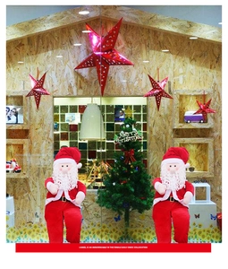 Detail of two sitting Santa Claus plush dolls in classic red suits for window display