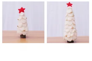 Detalle de árboles de Navidad de fieltro blanco con estrellas rojas y campanas en madera