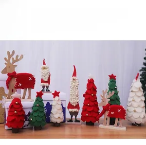 Primer plano de árboles de Navidad de fieltro y figuras de renos con base de madera