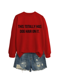 Close-up of red crewneck sweatshirt with black slogan and distressed denim shorts