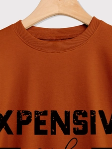 Close-up of caramel crew neck sweatshirt featuring vintage black 'EXPENSIVE' letter print