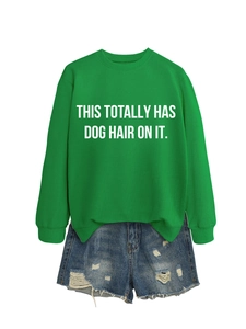 Detailed flat lay of green crewneck sweatshirt with white dog hair slogan and denim shorts