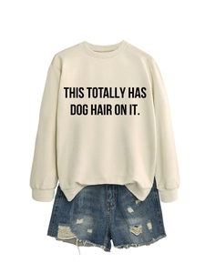 Flat lay of cream sweatshirt with dog hair quote and distressed denim shorts
