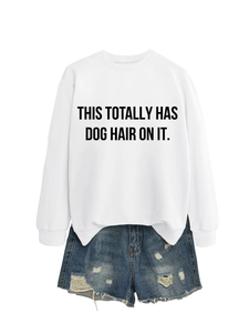 Detail of white crewneck sweatshirt with black slogan text paired with ripped denim shorts