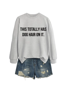 Close-up of gray crewneck sweatshirt with 'THIS TOTALLY HAS DOG HAIR ON IT' text and denim shorts