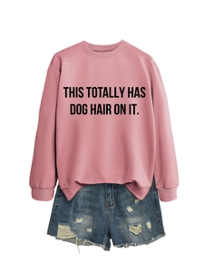 Close-up of pink long-sleeved sweatshirt with black text and distressed blue denim shorts