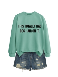 Detail of mint green sweatshirt with black slogan paired with frayed denim shorts