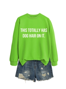 Detail of green crewneck sweatshirt with 'THIS TOTALLY HAS DOG HAIR ON IT' text and denim shorts