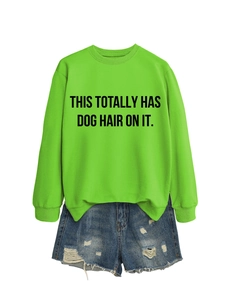 Flat lay detail of neon green crewneck sweatshirt with black printed slogan and denim shorts