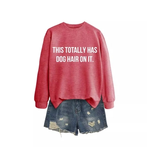 Red crewneck sweatshirt with dog hair slogan paired with ripped denim shorts