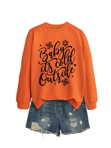 Detalle de sudadera naranja con estampado de texto y pantalones cortos denim deshilachados