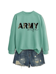 Détail du sweat vert menthe avec imprimé Army Wife et short en jean bleu délavé