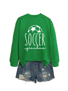 Detail of green Soccer Grandma sweatshirt paired with distressed denim shorts on white background