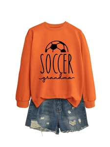 Detail of orange Soccer Grandma sweatshirt with side slit hem and distressed denim shorts